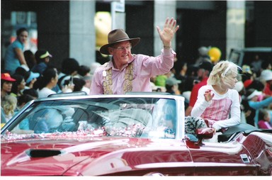 Julia Cotton; Santa 05; Stadium Santa? or Mad Hatter? Mayor Dick waves to the crowds at last years Santa Parade dressed as a cowboy in a convertible Cadillac